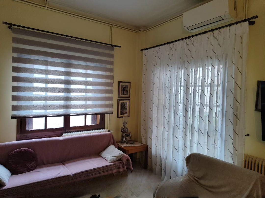 Σαλόνι με ρόλερ ζέβρα και λευκή διάφανη κουρτίνα